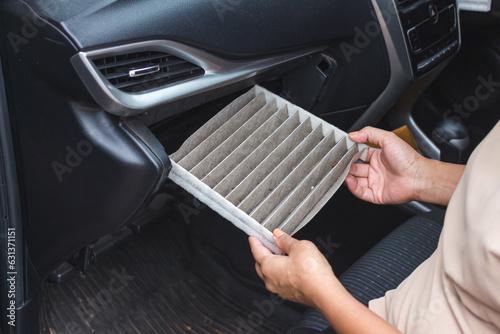 Women replacing cabin air conditioner filter of car.