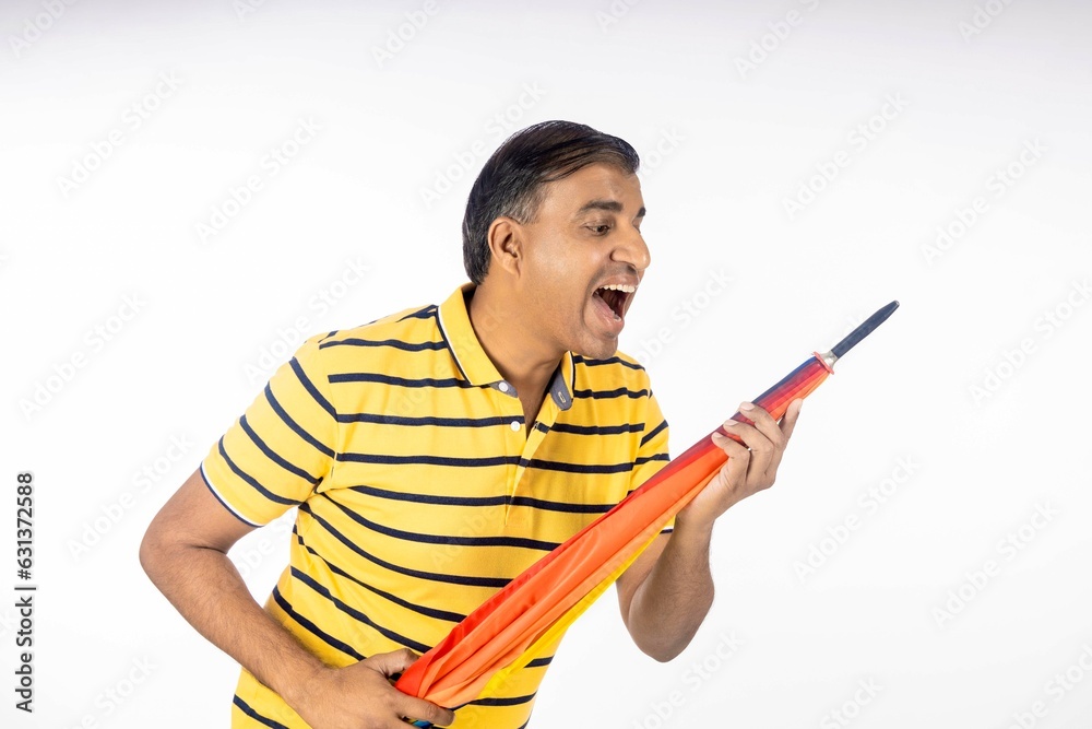 Indian man holding colorful umbrella in hand and giving happy expression. Indian man holding colorful umbrella in hand and giving happy expression.