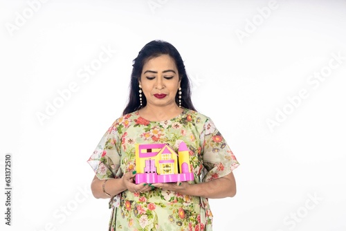 Indian woman holding home toy in hand. real estate concept.
