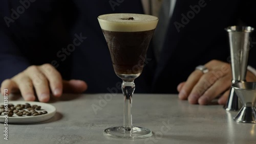 Bartender delivering an espresso martini at a bar table with a black background