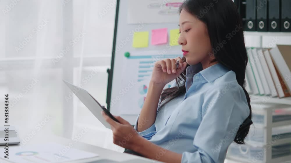 Young smart Asian businesswoman analyzing the document while working in the office room. Young smart Asian businesswoman analyzing the document while working in the office room.