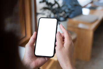 Mockup, woman's hand holding using mobile phone at coffee shop with copy space, white blank screen for text, mobile app design and advertising, online marketing