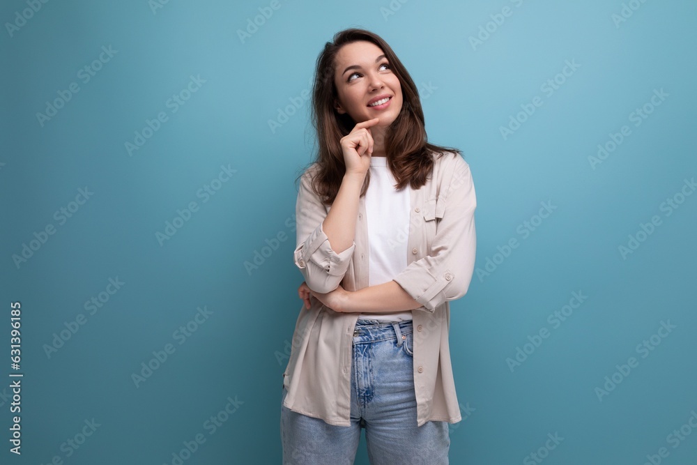 dreamy brunette young female adult in shirt and jeans on blue background dreamy brunette young female adult in shirt and jeans on blue background
