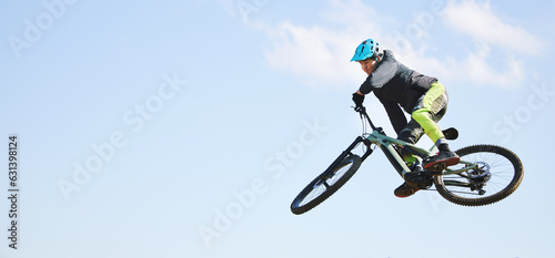 Mountain bike, man and jump in blue sky for competition, freedom or adventure on mockup space. Banner of athlete, sports and bicycle in air for action, cardio race and courage of stunt, speed or risk