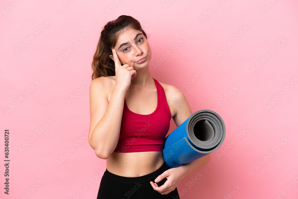 Young sport woman going to yoga classes while holding a mat thinking an idea Young sport woman going to yoga classes while holding a mat thinking an idea
