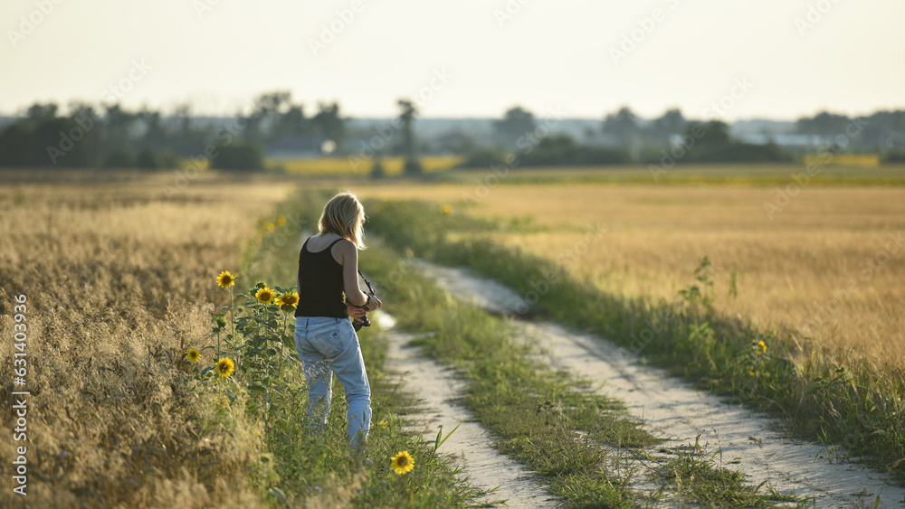 girl photographer photographing nature, walking in the field with sunflowers, back view. young woman in the wheat field. girl tourist. enjoying good weather. Rest, lifestyle, walk in the fresh air