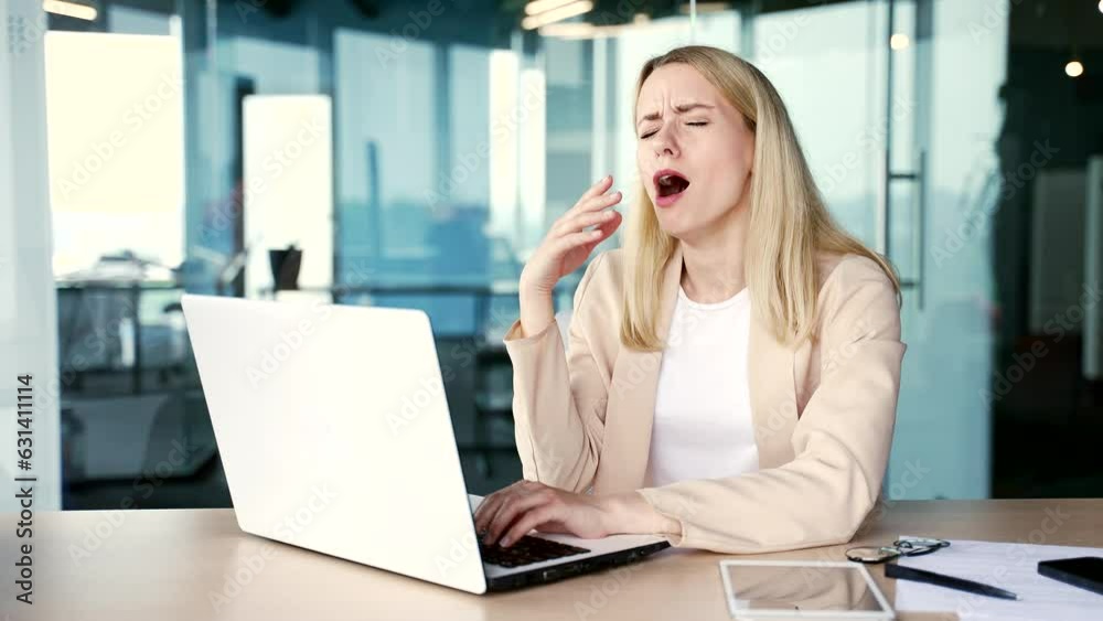 Overworked young female employee feels tired and wants to sleep working on laptop while sitting at workplace at desk in modern office. Sleepy exhausted woman yawns, closes her eyes. Overload at work Overworked young female employee feels tired and wants to sleep working on laptop while sitting at workplace at desk in modern office. Sleepy exhausted woman yawns, closes her eyes. Overload at work