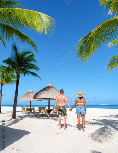 Man and Woman on a tropical beach with beach chairs and palm trees in Mauritius, a couple on a honeymoon vacation in Mauritius Le Morne Beach with Le Morne Mountain on the background