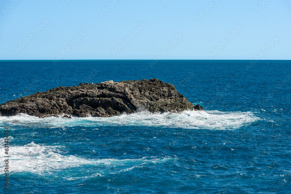 Cliff and Mediterranean Sea with white waves in front of the small village of Framura, La Spezia province, Liguria, Italy, Europe.