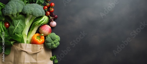 Fresh vegetables, fruits, greens, herbs, bread, and sausage laid out on an eco-friendly bag over