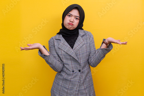 Portrait clueless of young Asian business woman shrugging shoulders, looking confused, know nothing, standing over yellow background