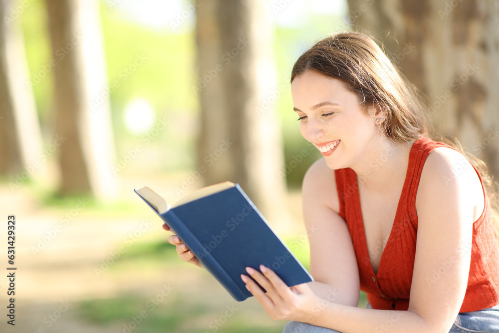 Obraz premium Happy woman checking a paper book in a park