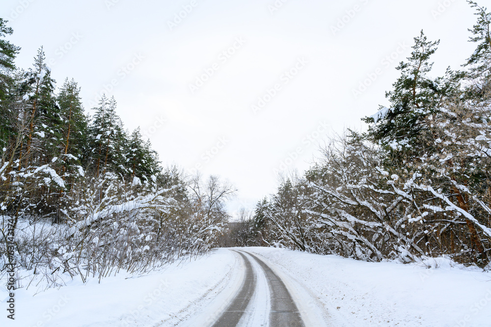 Obraz premium Snowy winter road in a mountain forest.