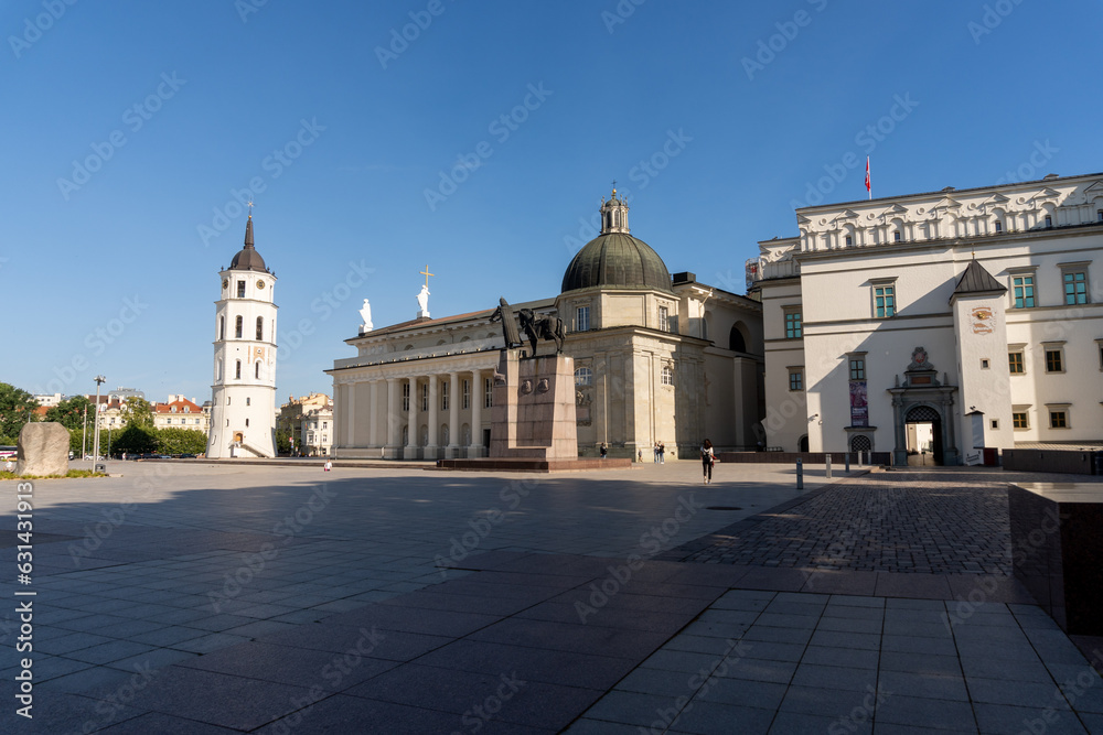 Vilnius Cathedral Square, in the morning on a sunny day, with some people walking around the square.
