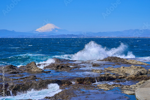 神奈川県藤沢市江の島の稚児ヶ淵から岩礁に打ち寄せる波と富士山を見る