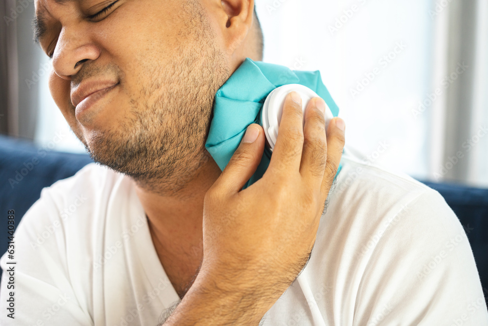 Obraz premium Young asian man is sick has a fever is hot has a cold body aches gives a hot and cold water bag to compress to alleviate the illness and reduce fever.