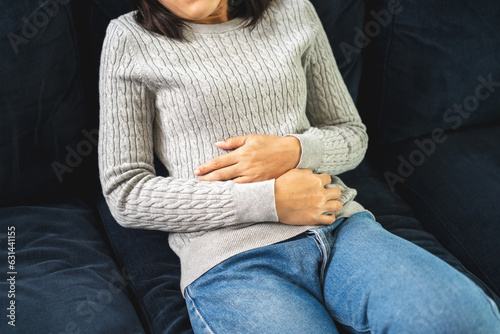 Woman had a stomach ache menstrual pain and gastritis inflammatory bowel disease. She put hand on his stomach and squeezed it to relax and soothe has go to toilet need to poop photo