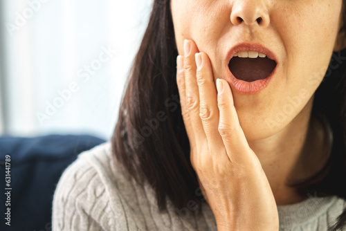 Asian woman puts his hand on mouth and feels toothache because of tooth decay sensitive teeth gives hot water bag. Problems with teeth bad breath.