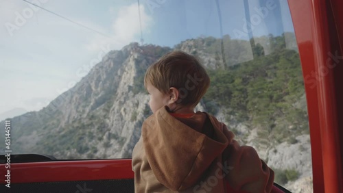 Interested tourist boy sitting in funicular cabin of cable car in Turkey. Vacations travelling in mountains admiring breathtaking views.