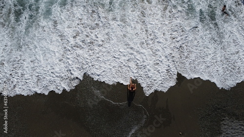 Fotografia aerea di giovane donna sulla spiaggia con costume sportivo da nuoto bagnata dalle onde dell'oceano - Vacanza al mare 