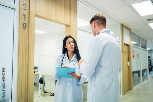 Female Surgeon and Doctor Walk Through Hospital Hallway, They Consult Digital Tablet Computer while Talking about Patient's Health.