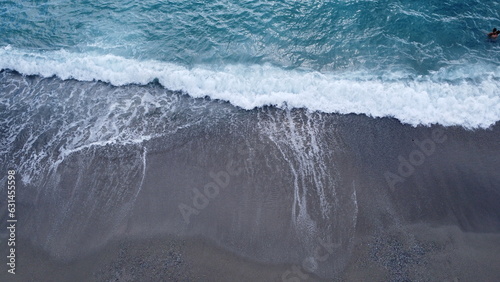 Foto aerea del mare e la spiaggia - Vista dall'alto delle onde del mare che si infrangono contro il bagnasciuga della spiaggia durante il mare in tempesta - Mare mosso photo