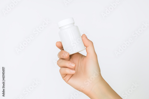 female hand holds a white plastic jar with pills. health care and medicine concept
