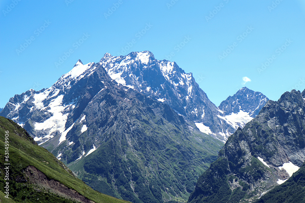 Mountain landscape: snow-capped mountains on a sunny summer day, in the foreground - mountains with vegetation