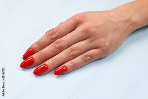 red nails  manicure  female hand  arm close up view on blue background