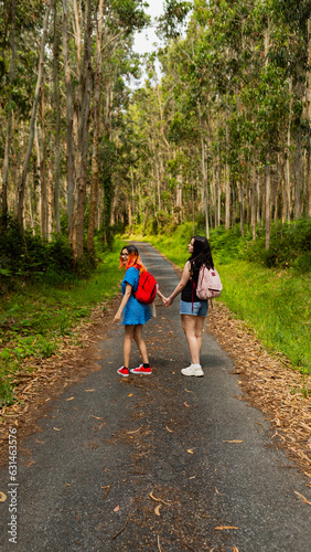 A couple of young lesbian women walk hand in hand along a rural path during a nature excursion in Galicia