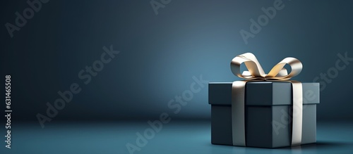 side view monochrome image of a small luxury gift box with a blue bow on a dark blue background.