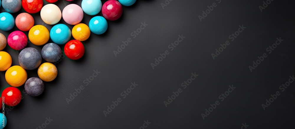 Colorful candy balls placed on a gray and black paper background, arranged as a horizontal banner Colorful candy balls placed on a gray and black paper background, arranged as a horizontal banner