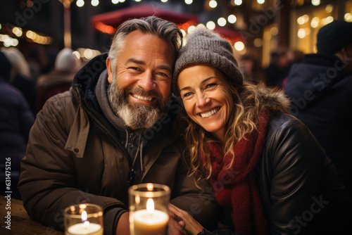 Beautiful couple having wonderful time on traditional Christmas market on winter evening. Woman and man enjoying themselves in Christmas town decorated with lights.