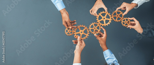 Slika na platnu Panoramic shot top view of business people holding cog wheel as unity and teamwork in corporate workplace concept