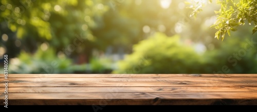 A wooden table with no objects on it and a blurred background of an outdoor garden. It provides