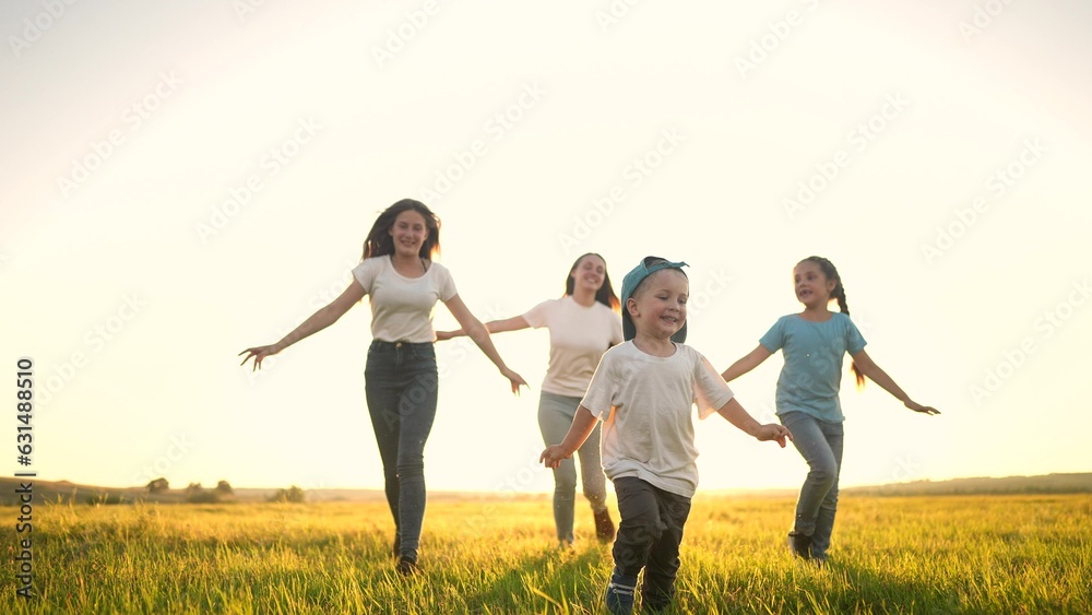 happy family. people in the park. children child running together in the park on the grass silhouette. daughter and son are running. happy family and little child in sunset summer. concept dream happy family. people in the park. children child running together in the park on the grass silhouette. daughter and son are running. happy family and little child in sunset summer. concept dream