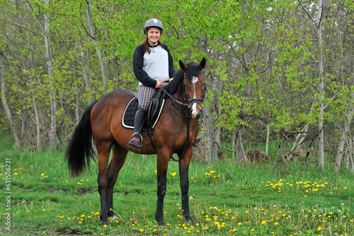 Jockey girl riding a horse in the summer outdoors.