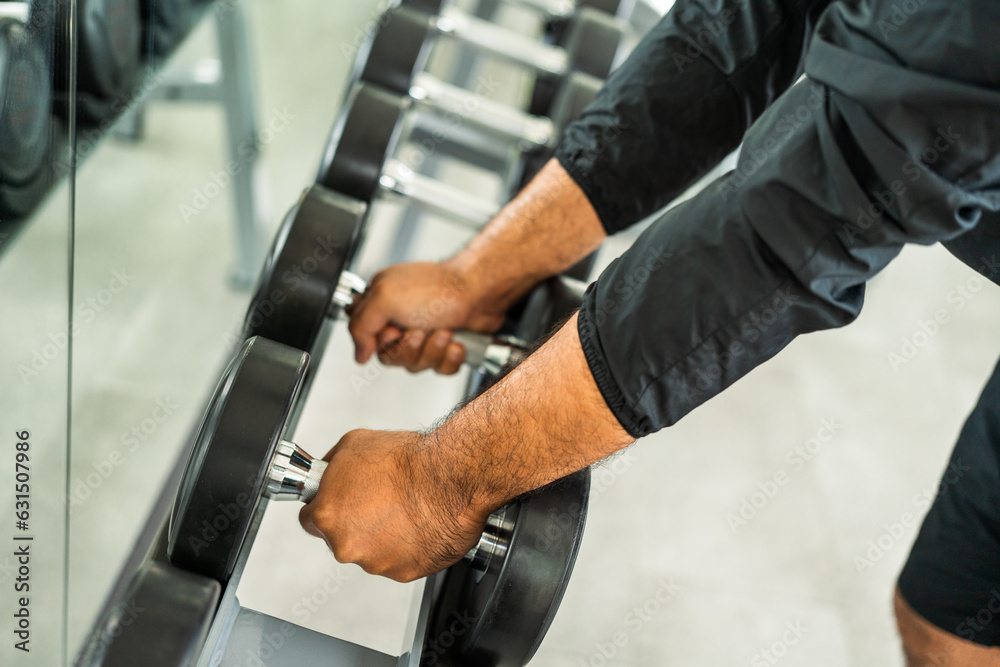 Guy weight training wearing sportswear. Asian man exercise indoor gym lifting dumbbell. Bodybuilder good health. Young Fitness man with dumbbell in gym.