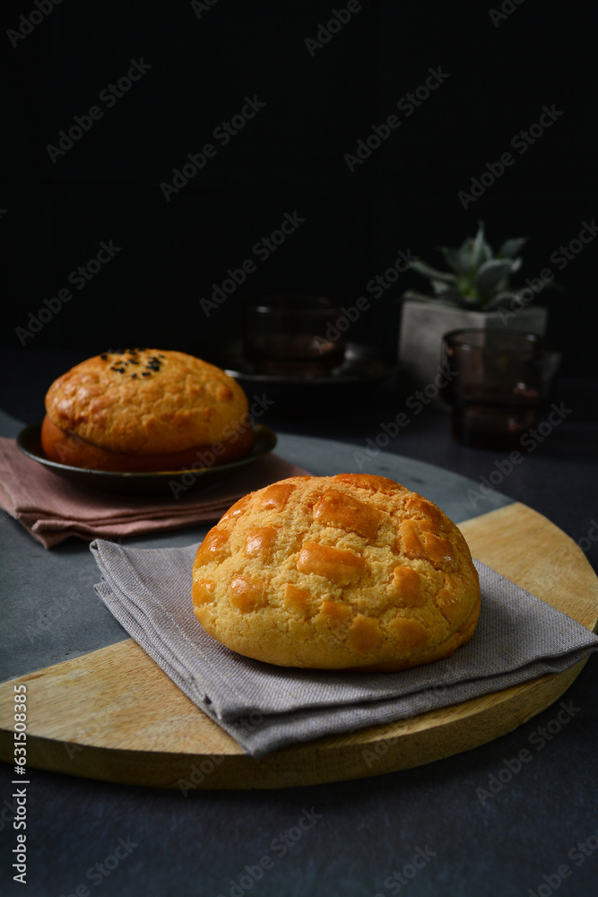 freshly handmade baked Macau crispy round polo bun bread w red bean paste on dark black luxury background with ceramic decoration halal food dessert menu for cafe freshly handmade baked Macau crispy round polo bun bread w red bean paste on dark black luxury background with ceramic decoration halal food dessert menu for cafe