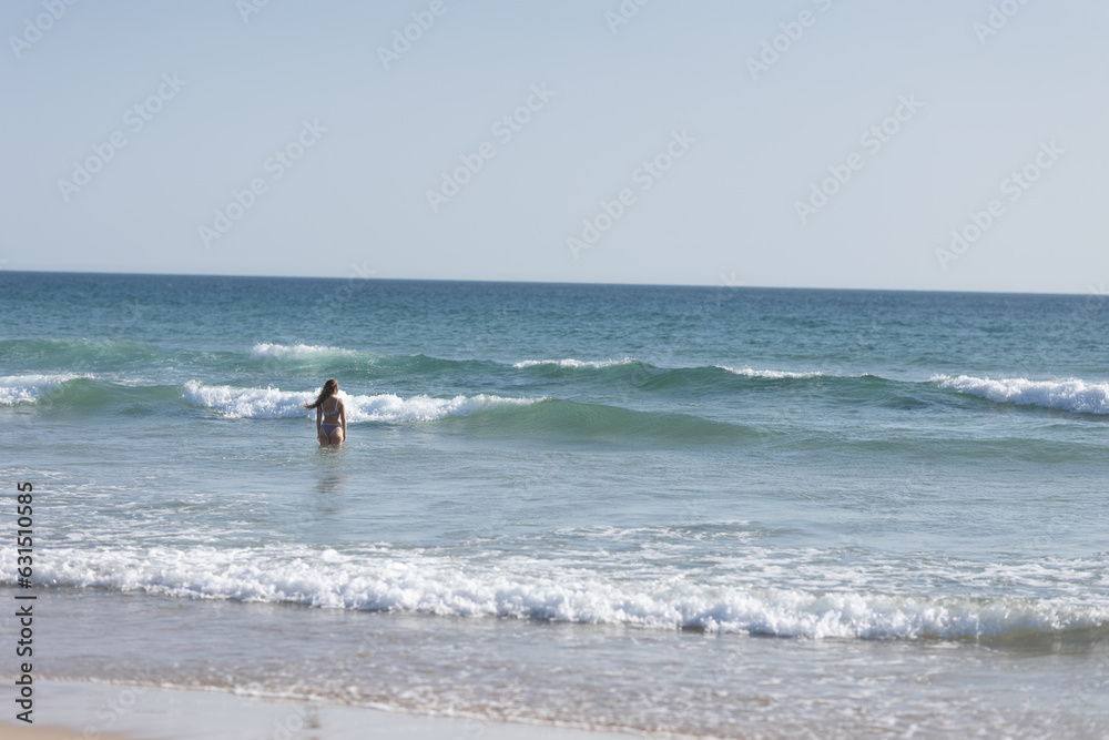 A young woman with nice body standing in the ocean - back view A young woman with nice body standing in the ocean - back view