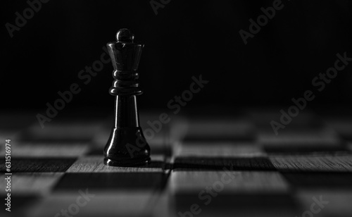 Foto Selective focus grayscale shot of a black queen piece on a chess board