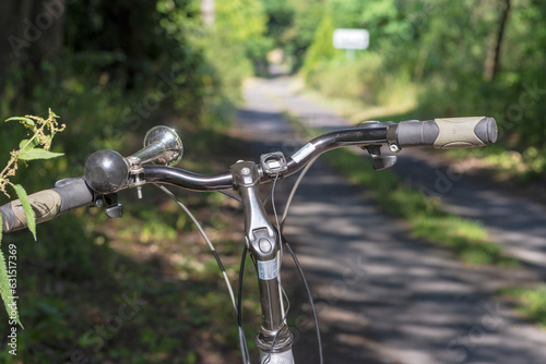 Turystyczny ( trekingowy) rower na leśnej drodze widoczna kierownica i stalowa rowerowa trąbka . 