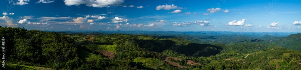 Wide panoramic view of mountains with blue sky.