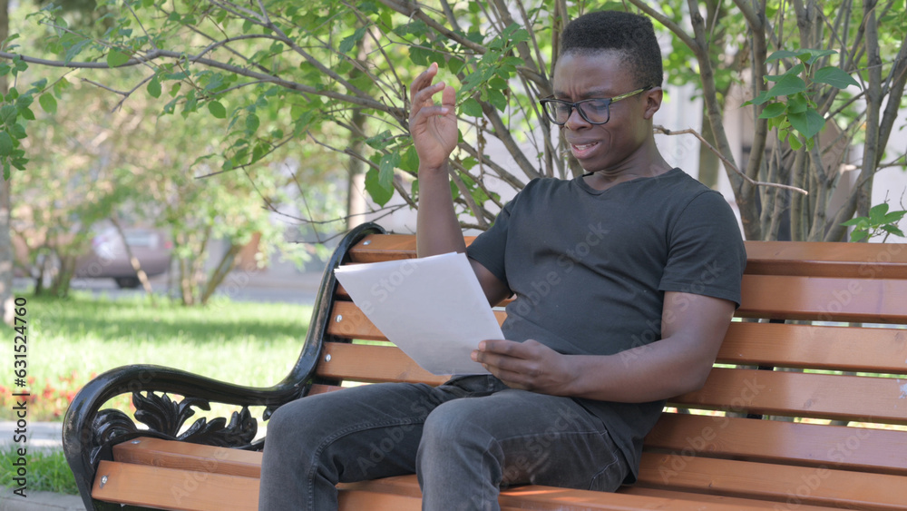 Fototapeta premium Young African Man Feeling Upset while Reading Contract Outdoor