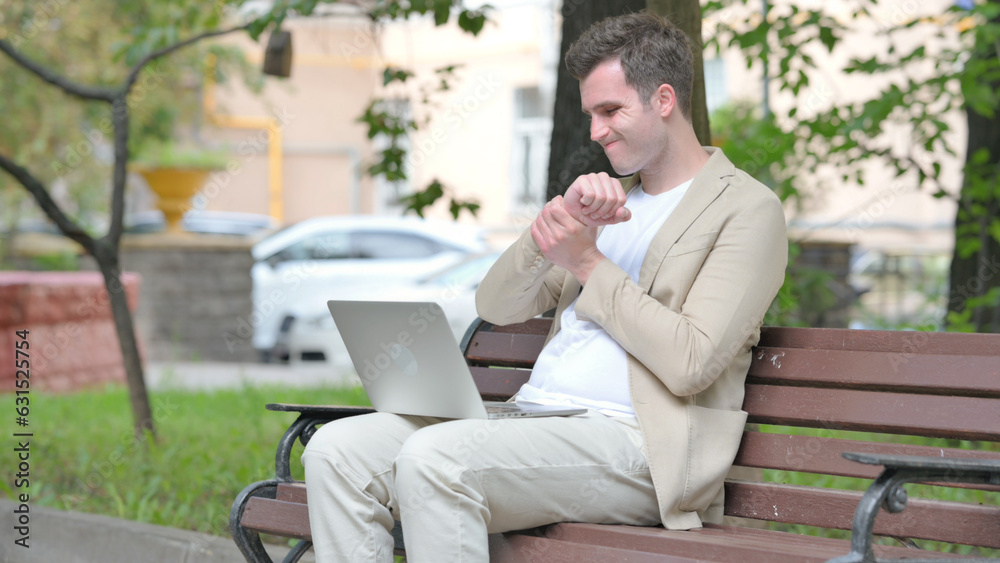 Fototapeta premium Casual Young Man with Wrist Pain Working on Laptop Outdoor