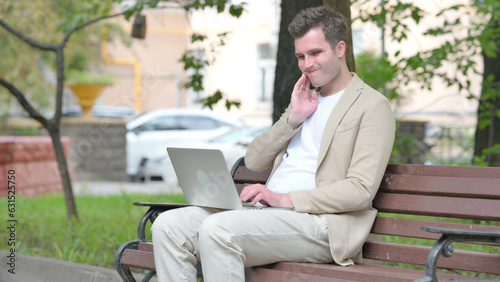 Casual Young Man with Toothache Working on Laptop Outdoor