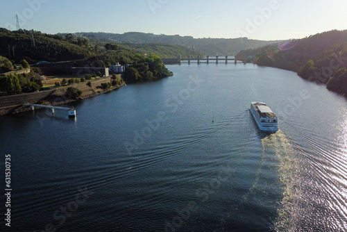 Cruise ship travel the waters of the Douro River, with the Crestuma dam in background. Portugal, 2023