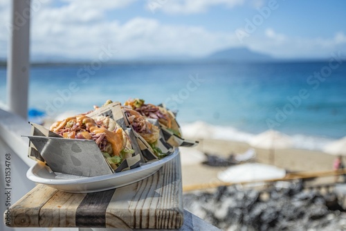 Photography Plate of freshly prepared tacos on a wooden railing, overlooking the ocean at a