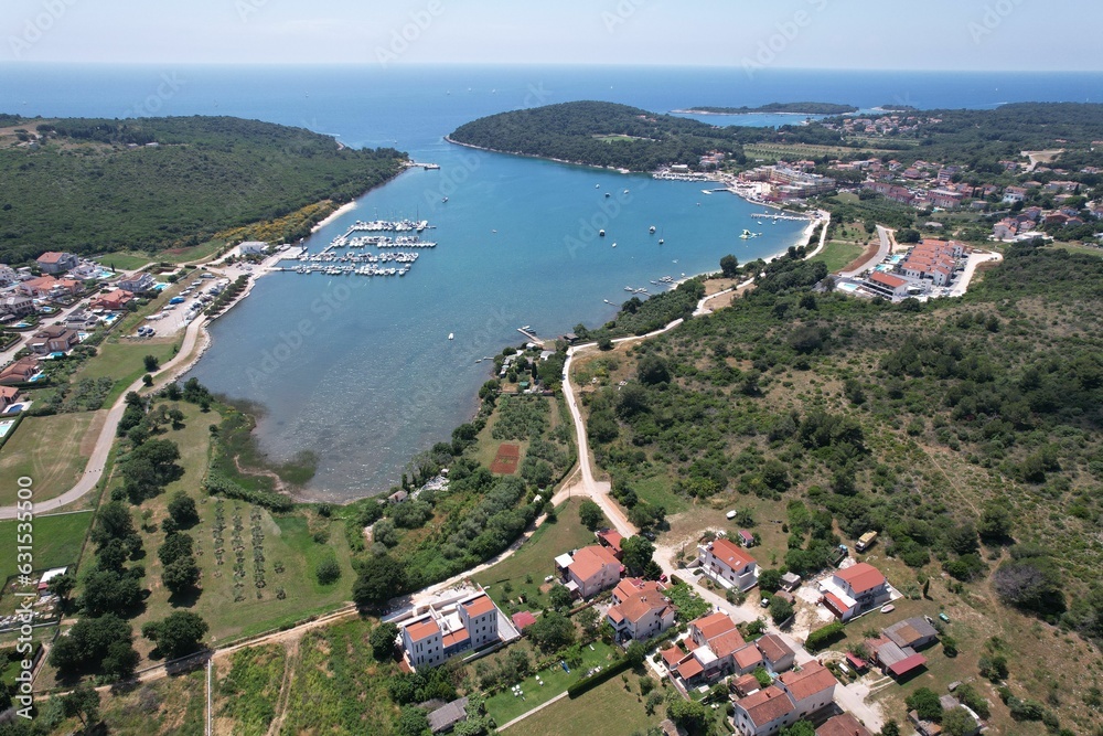 Aerial shot of a coastal town and marina with urban buildings and a port in Volme, Croatia