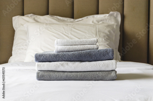 stack of folded terry towels lies on clean white bed. Cleaning in guest room of hotel, cleanliness